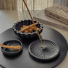 black scalloped bowl standing on round black big tray together with palo santo and incense holder