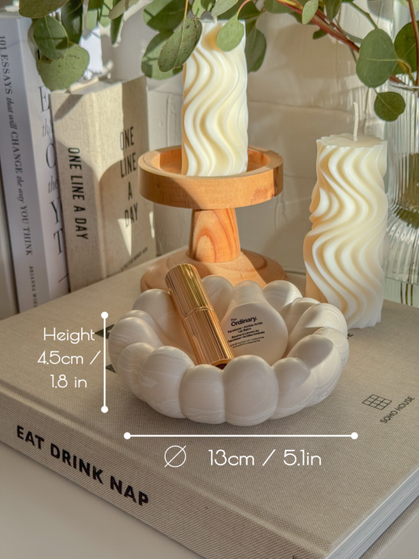 Scalloped Bubble Bowl lying on a Eat Drink Nap book surrounded by minimalist decor and candles